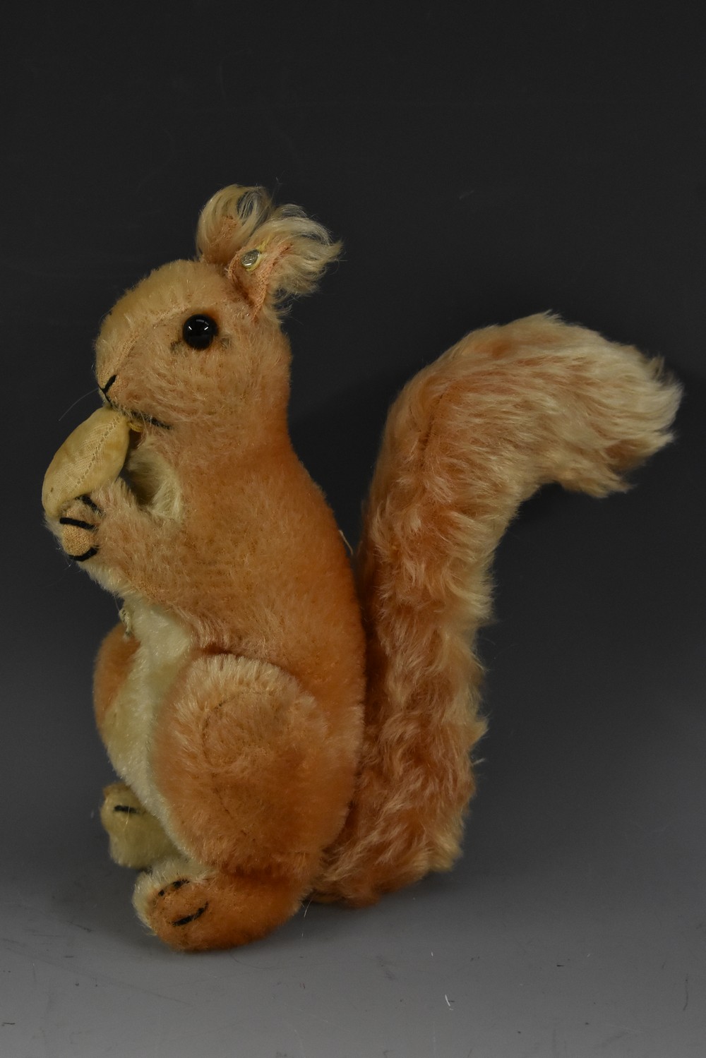 Steiff Toys - a mid 20th century stuffed toy, Squirrel Eating a Nut, button to ear, 21cm high, c.