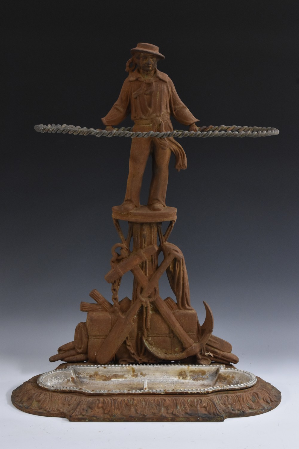 A 19th century cast iron walking stick stand, as a sailor, standing above a maritime trophy,