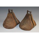 A pair of Chilean iron bound hardwood stirrups, chip-carved with stylised flowers and leaves,