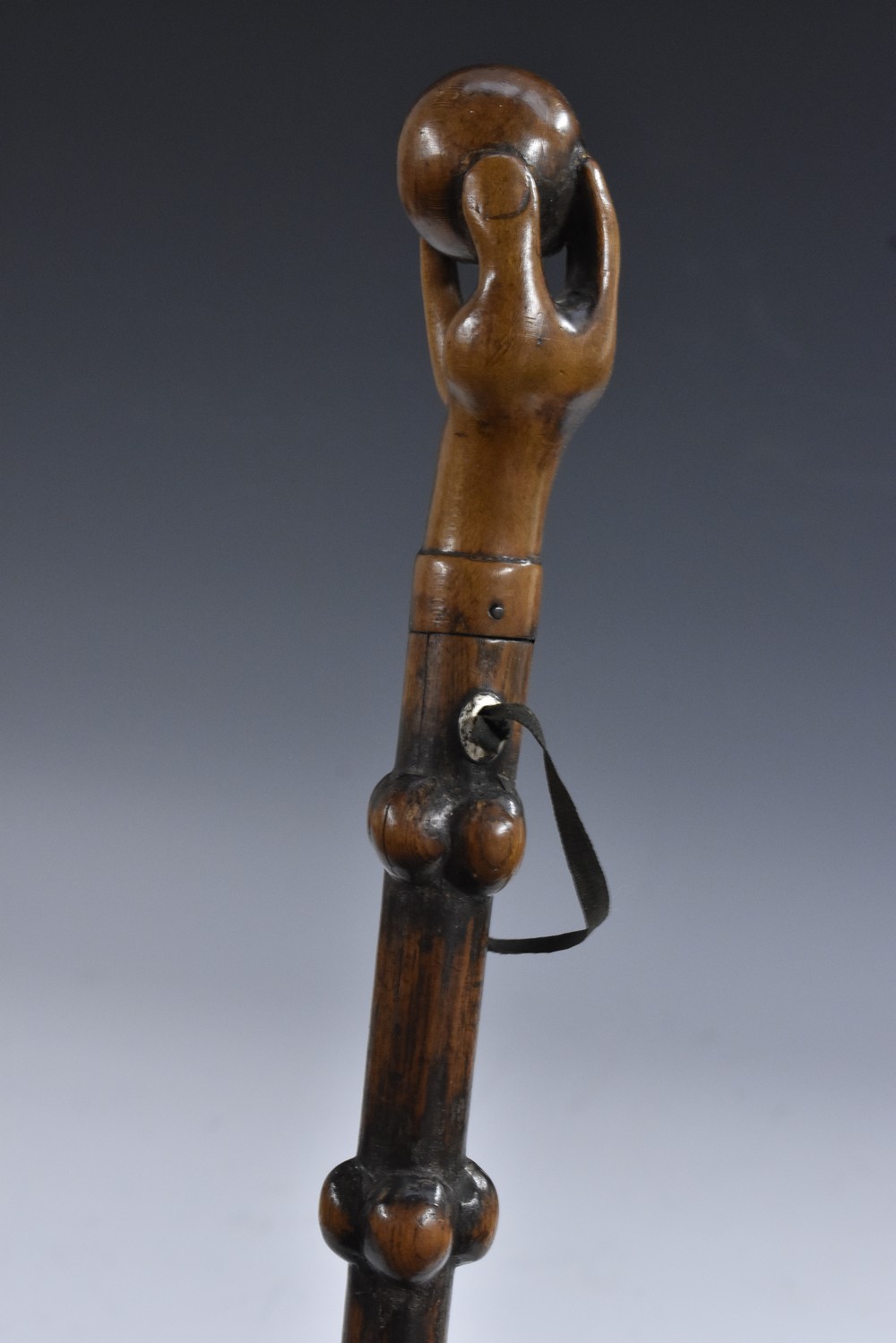 A 19th century folk art walking cane, the fruitwood pommel carved as a hand grasping a ball,