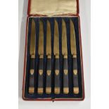 A set of six 19th century gilt metal tea knives, ebony hafts inlaid with shield shaped cartouches,