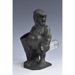 An early 20th century dark patinated spelter novelty spill holder, as a golf caddy in caricature,