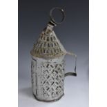 A 19th century vernacular tin candle lantern, conical canopy, hinged door, angular handle,