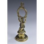 A 19th century brass pocket watch stand, as a scantily clad putto, kneeling, holding a chaplet,
