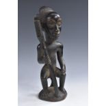 Tribal Art - a Yoruba figure, seated on a stool holding a staff, domed base, 28cm high,