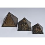 A set of three graduated pyramid desk models, each decorated in gilt with Egyptian devices,