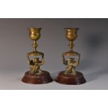 A pair of 19th century gilt bronze novelty candlesticks, each sconce held aloft by a monkey,