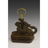 A Regency cast iron door stop, cast as a griffin, the brass loop handle as a fist and serpent,