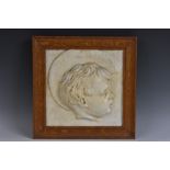 An early 20th century plaster relief plaque, of a young boy with a halo, in profile, 27cm x 27.