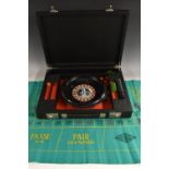 A roulette wheel, 25cm diam, cased, chips and baize playing surface ensuite,