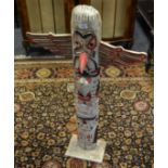 A softwood totem pole, painted in white, picked out in red and black,