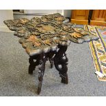 A Teak occasional table shaped top, carved in relief with fruiting vines,