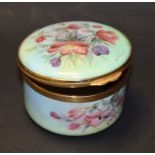 A Kingsley enamel circular box and hinged cover, painted overall with garden flowers,