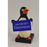 A Carlton Ware Penguin lamp, standing holding a sign, Draught Guinness, 17.