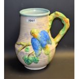 A Clarice Cliff jug, in relief with a budgerigar, in blue and green, rustic handle, 22.
