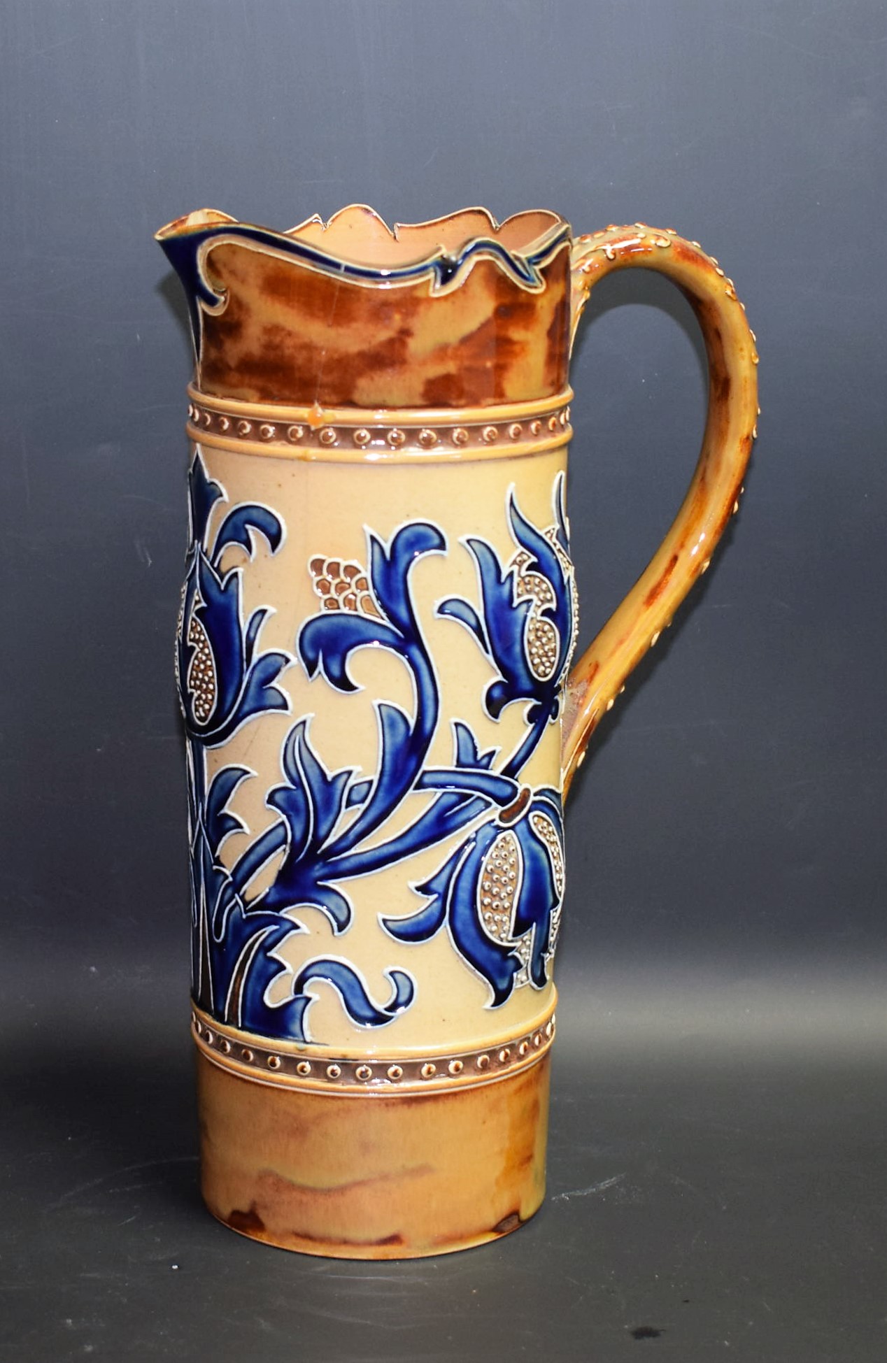 A Doulton Lambeth cylindrical jug, designed by Mark V Marshall, incised with stylised thistles,