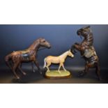 A Royal Doulton Palamino horse, on stand, boxed; a leather covered study of a horse; another,