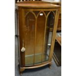 A 1940's bowfront display cabinet, astragal glazed door enclosing shelving.