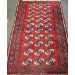 A hand woven Tekke Torkmen rug decorated with geometric lozenges and banded border on a red ground.