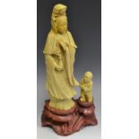 A large soapstone carving Guanyin and child attendant, red stone base, 35.
