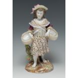 A Berlin figure, of a young lady, wearing a broad brimmed hat and floral skirt,