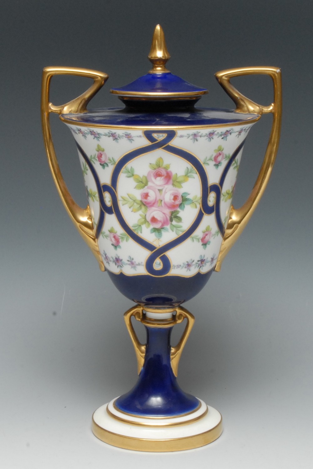 A Mintons two handled pedestal ovoid vase, decorated with roses within a blue ribbon cartouche,
