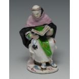 A Bow figure of a monk, seated, the monk reading from a Bible, in colours,