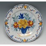 A Delft dish/charger, painted in bold polychrome enamels with a basket of flowers and foliage,