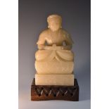 A Chinese pale soapstone carving, of a Buddhistic figure, seated in a lotus,
