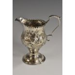 A George III silver baluster cream jug, chased with baskets of fruit and stiff leaves,