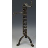 A Medieval style candlestick, of spiralled form, triform legs,