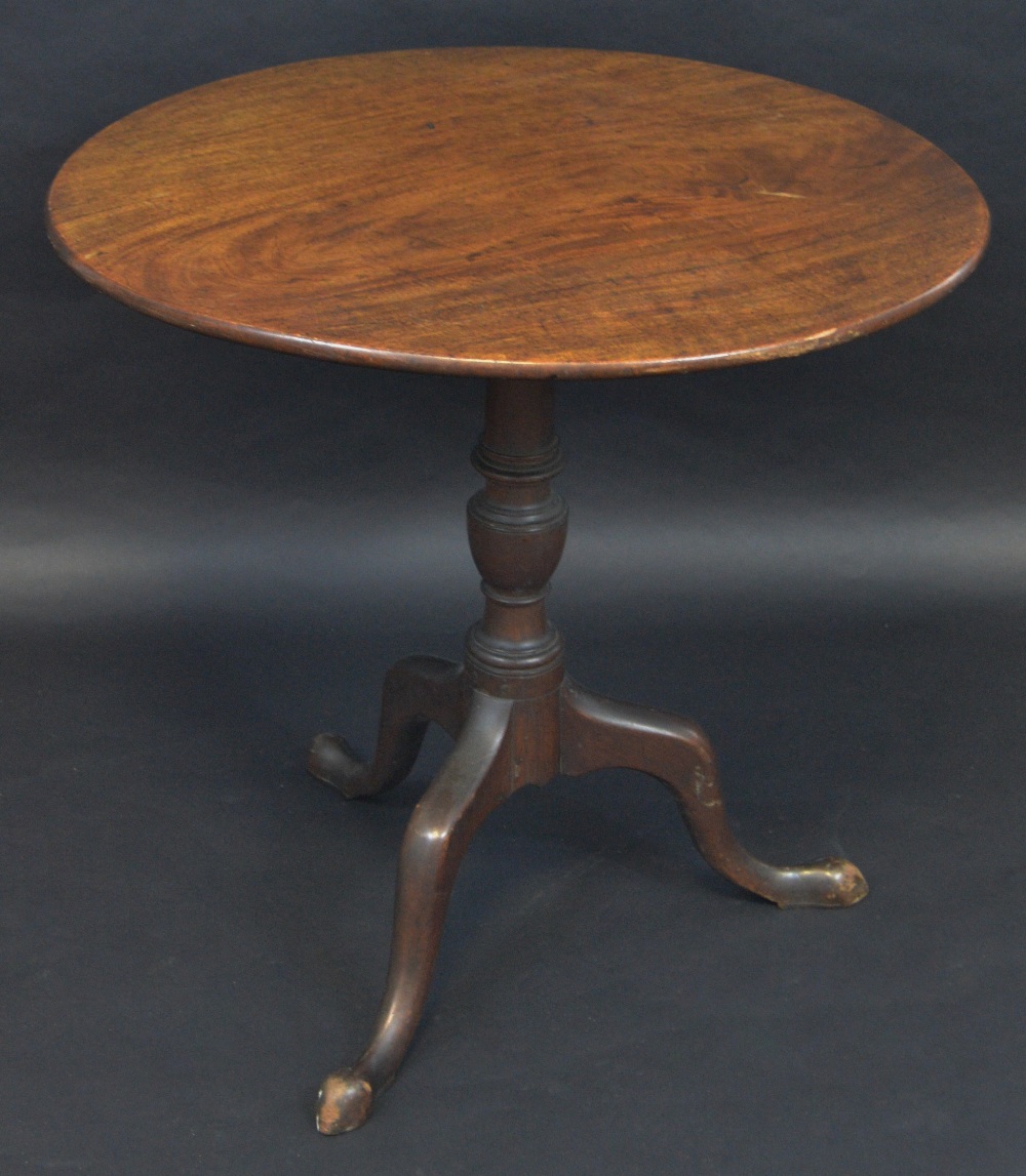 An 18th century mahogany occasional table, the one piece circular top tilting on a turned column,