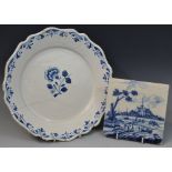 A Dutch Delft tile, decorated in cobalt blue with figures by a river, before a church,