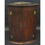 An 18th century bow front oak corner cabinet, stepped cornice, two doors, H hinges, 99cm high,