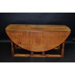 A substantial Nigel Griffiths oak double gateleg drop leaf table, circular top, turned legs,