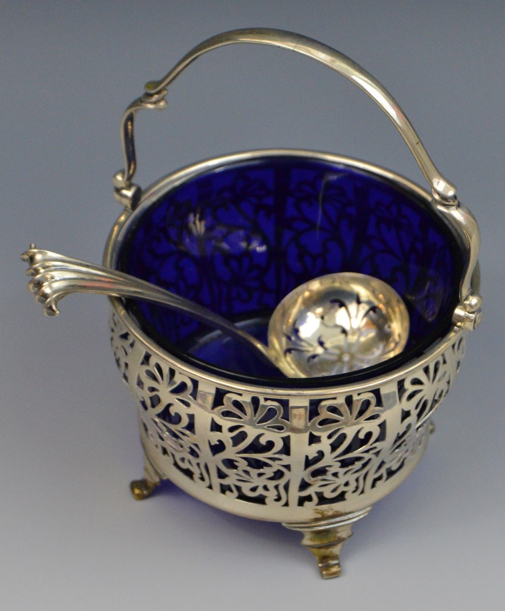 A silver ogee basket, pierced, swing handle, blue glass liner, 14cm high,