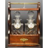 A mahogany two bottle tantalus, comprising two cut glass decanters, two Coalport labels,