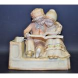 An Amphora figure group, of two Dutch children seated reading a book, in blush ivory,