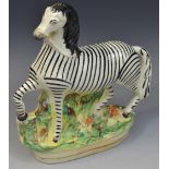 A Victorian Staffordshire model, of a zebra, standing to the right, gilt lined oval base, 22cm high,