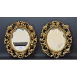 A pair of late 19th century Rococo style oval gilt framed wall mirrors, bevelled plate,