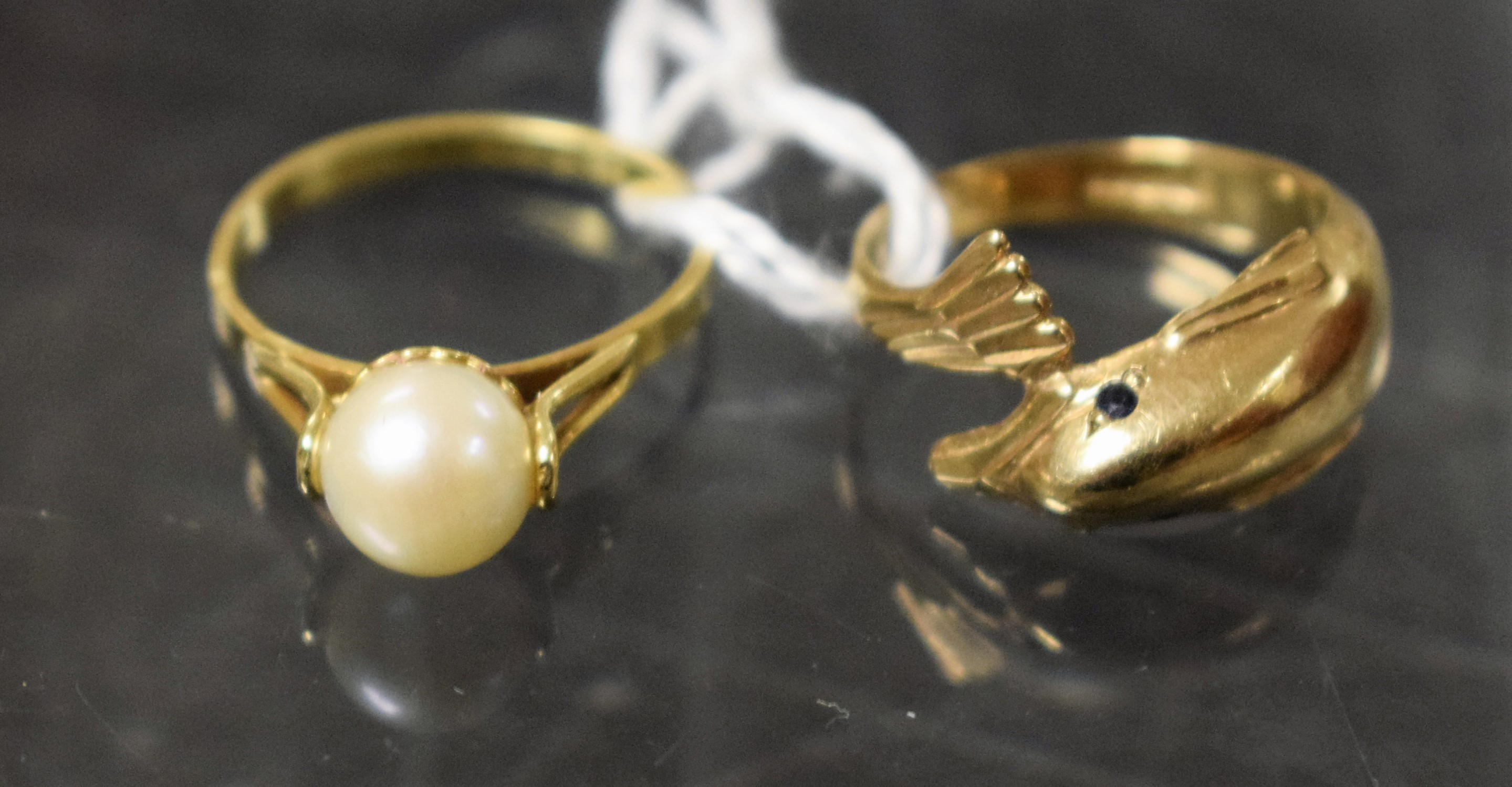 A 14ct gold ring, set with a single pearl, 1.8g; a 9ct gold dolphin ring, 2.