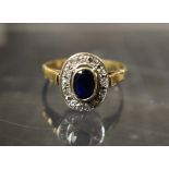 A sapphire and diamond oval cluster ring, central deep blue oval collar set sapphire,