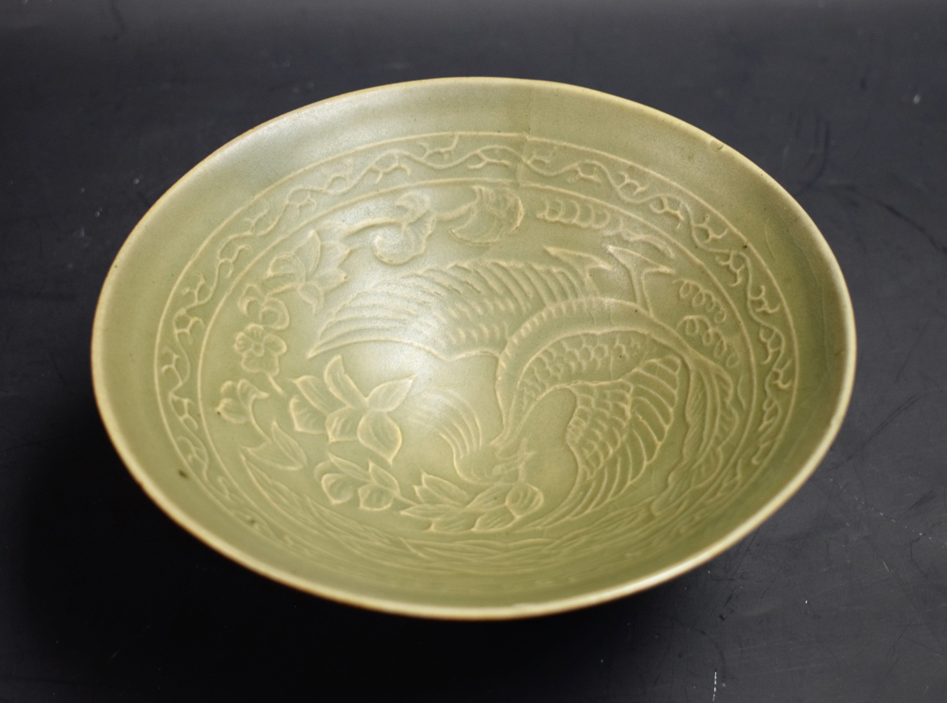 A Chinese Yaozhou type celadon conical bowl, moulded in shallow relief with a phoenix,