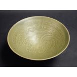 A Chinese Yaozhou type celadon conical bowl, moulded in shallow relief with a phoenix,