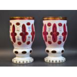 A pair of late 19th century Bohemian ruby glass vases, overlaid in white and painted flowers,