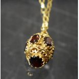 A 9ct gold egg shaped pendant necklace, pierced and set with facet cut garnets; fine link chain, 8.