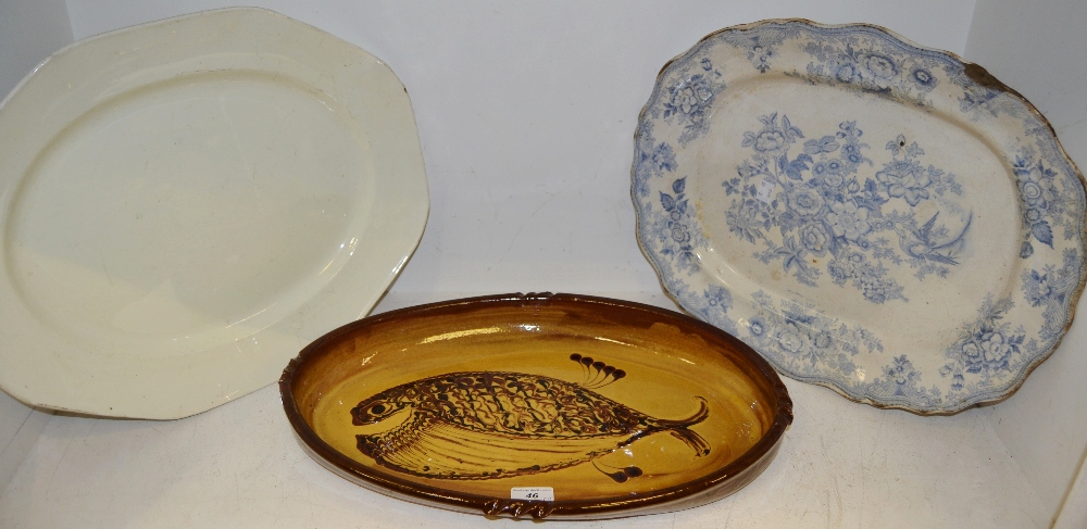 An oval slipware dish decorated with a stylized fish; a blue and white meat plate;