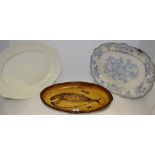 An oval slipware dish decorated with a stylized fish; a blue and white meat plate;