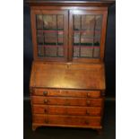 A George III oak bureau bookcase, stepped cornice over two glazed doors enclosing shelving to top,