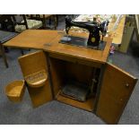 An early/mid 20th century Singer sewing machine in cabinet;